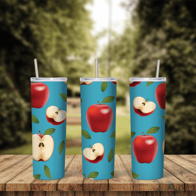An apple tumbler wrap with red apples, apple halves showing seeds and green leaves scattered over a bright blue background. Sublimation design