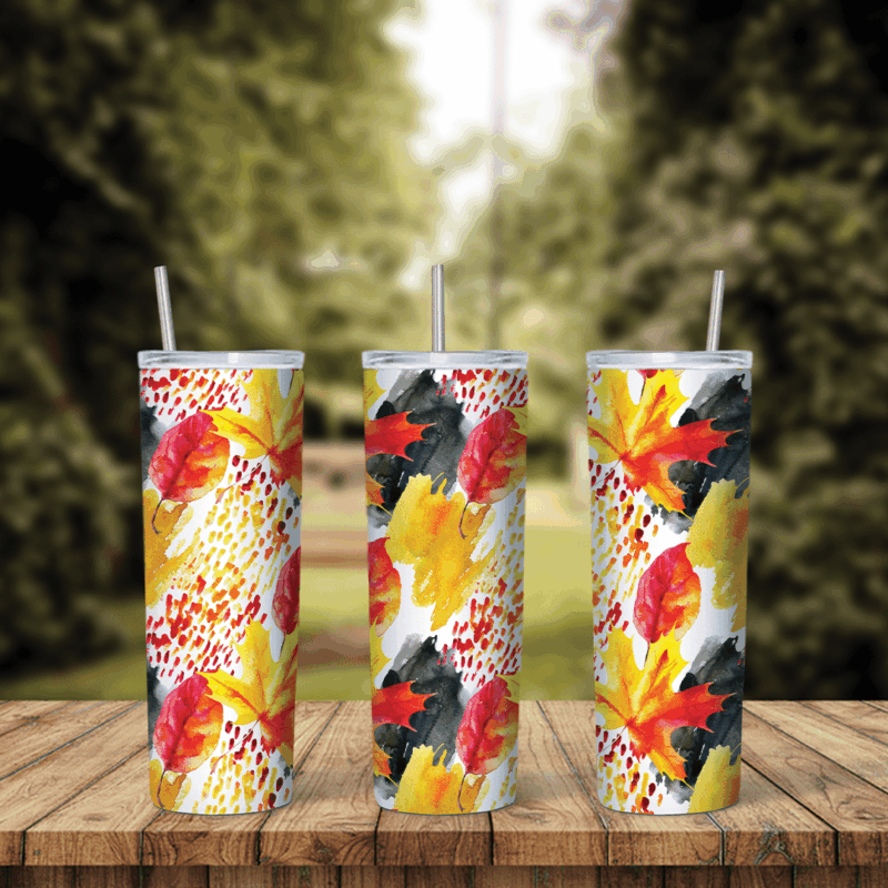 A full 20 oz skinny tumbler wrap with red and yellow maple leaves, black brush strokes and red speckles on white. Sublimation design