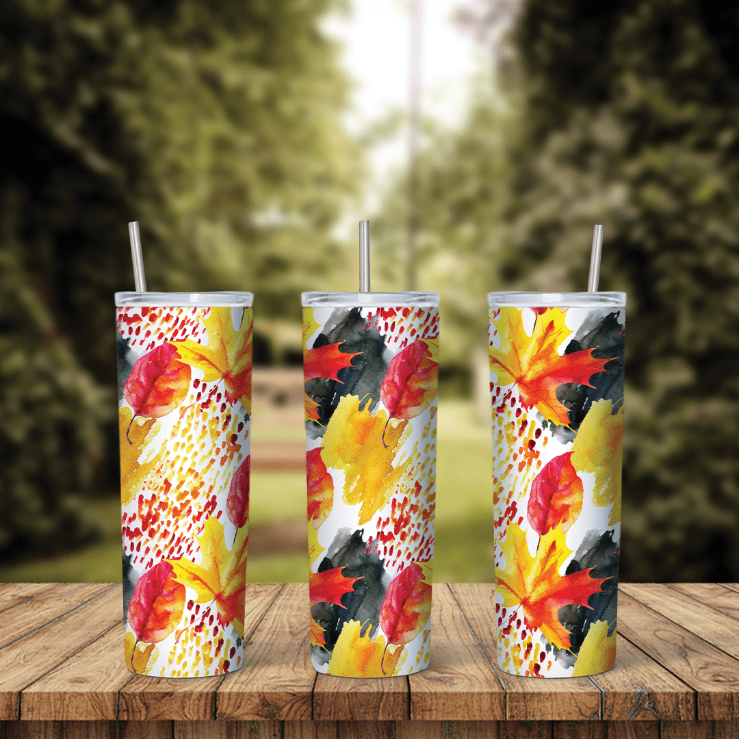 A full 20 oz skinny tumbler wrap with red and yellow maple leaves, black brush strokes and red speckles on white. Sublimation design