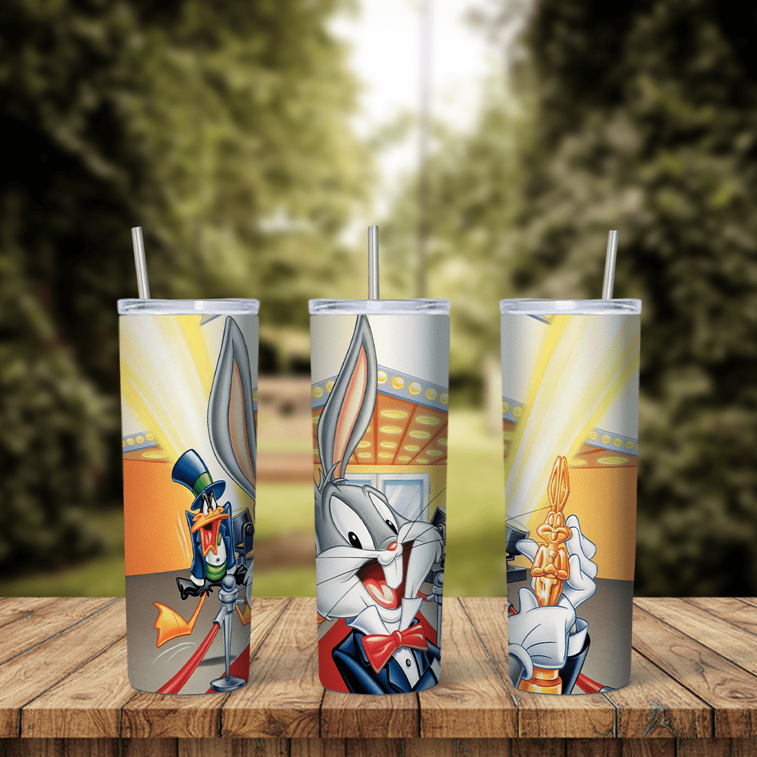 A full 20 oz skinny tumbler wrap of Bugs Bunny in a tuxedo, Daffy Duck in a top hat and a golden award statue under stage. Sublimation design