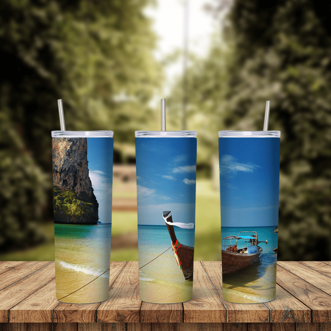 A full 20 oz skinny tumbler wrap with a tropical beach scene: a wooden longtail boat on clear water, a limestone cliff and golden. Sublimation design