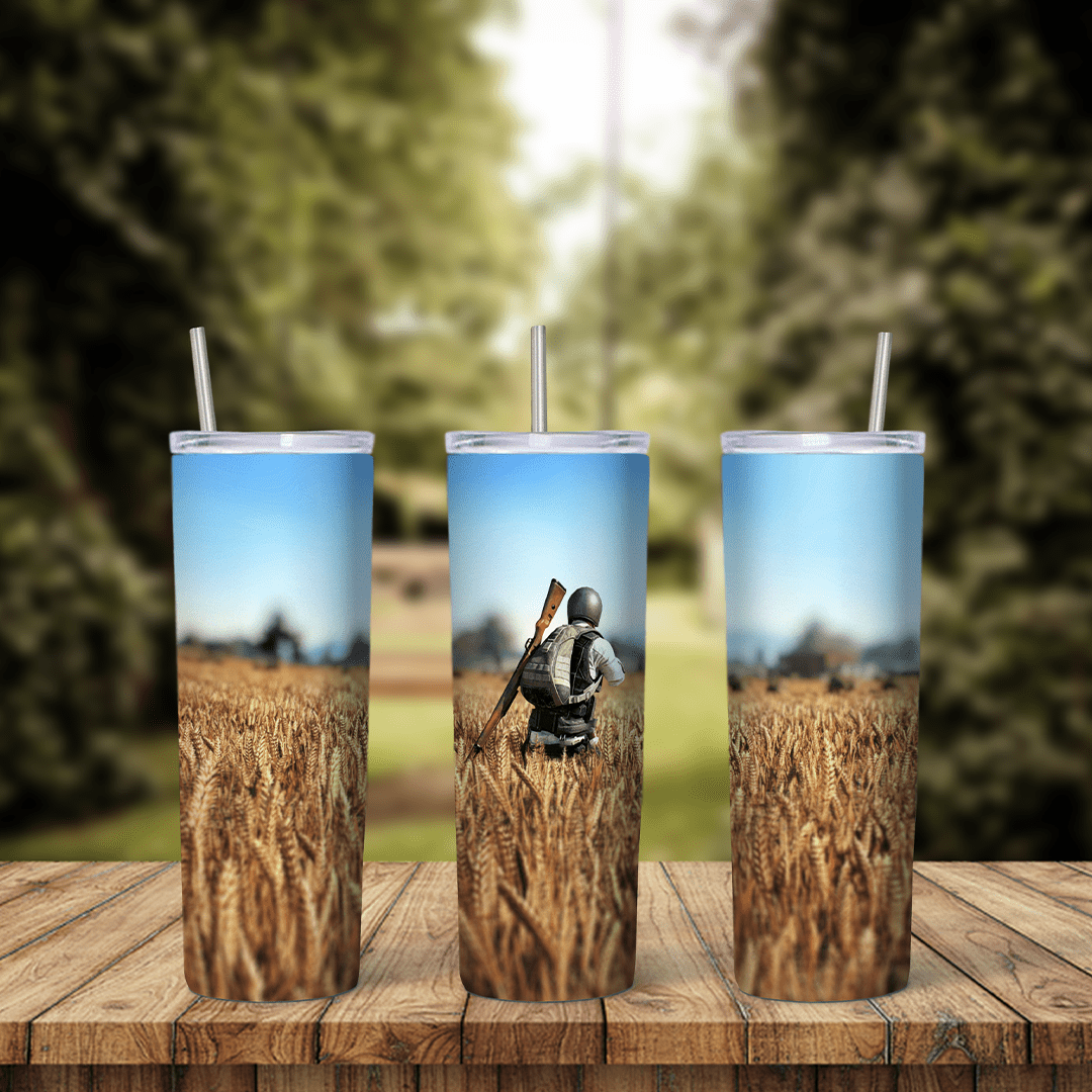 A full 20 oz skinny tumbler wrap with PUBG game art: a player with a backpack and rifle standing in a golden wheat field under. Sublimation design