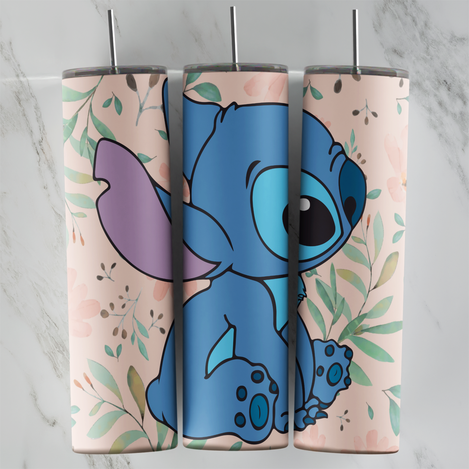 A 20 oz skinny tumbler wrap with Stitch sitting and looking back over his shoulder, framed by soft green leaves on a pale peach. Sublimation design